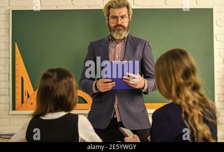 Enseignant et enfants en classe. Dialogue et communication. La vie scolaire quotidienne. Des amis étudient ensemble. Retour à l'école. Aide et assistance. Enseignant de niveau élémentaire. Groupe de discussion des enfants et des enseignants. Banque D'Images