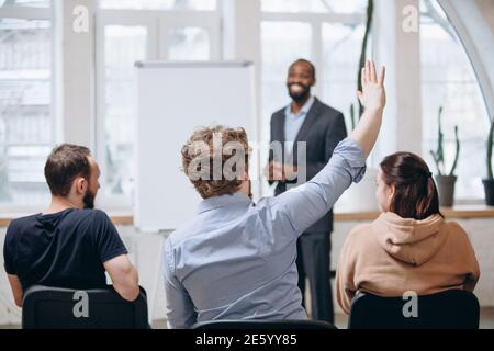 Concentrez-vous sur l'étudiant. Conférencier masculin donnant une présentation dans le hall de l'atelier universitaire. Audience ou salle de conférence. Vue arrière des participants non reconnus. Scientifique, événement d'affaires, formation. Éducation Banque D'Images