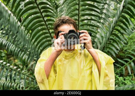 Jeune garçon en manteau de prendre des photos dans la forêt pendant le voyage Banque D'Images