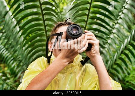 Jeune garçon en manteau de prendre des photos dans la forêt pendant le voyage Banque D'Images