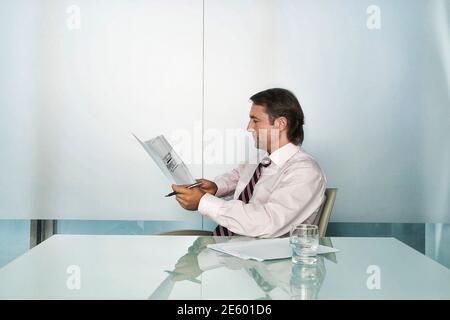 Homme d'affaires lisant le document à la table de conférence Banque D'Images