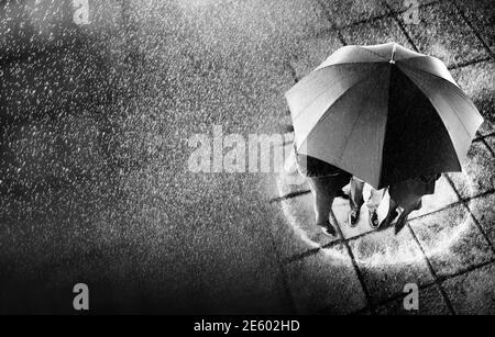 Photo en noir et blanc des hommes d'affaires qui se rangent sous un parapluie Banque D'Images