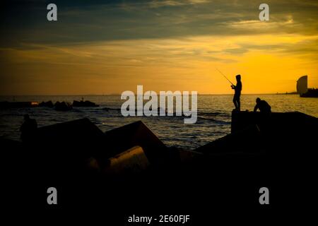 Barcelone, Espagne. 28 janvier 2021. Les navetteurs pêchent dans un brise-lames sur le front de mer de Barcelone au coucher du soleil Credit: Matthias Oesterle/Alamy Live News Banque D'Images