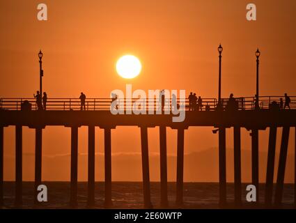 Coucher de soleil paysage avec des silhouettes de personnes sur Huntington Beach Pier dans le comté d'Orange, Californie, États-Unis Banque D'Images