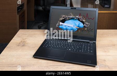 Main d'aide avec la seringue dépassant du trou dans l'écran cassé de l'ordinateur portable avec graphique Covid-19. Médecin virtuel symbolique. Espoir de vaccin contre la maladie du coronavirus. Banque D'Images