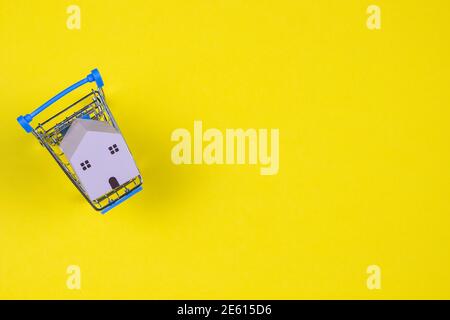 Maison en bois à l'intérieur d'un mini panier sur fond jaune. Vue de dessus Banque D'Images