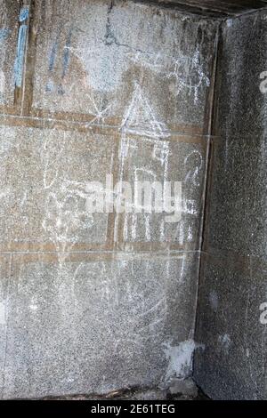 Dessin de craie blanche pour enfants d'une maison et du soleil sur un mur extérieur en béton gris Banque D'Images