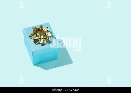 Cadeau bleu avec noeud doré sur le bleu pastel anniversaire de fond ou autre célébration Banque D'Images