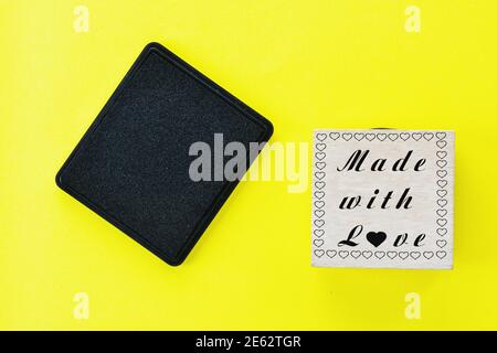 Timbre en bois fait dans l'amour et noir sur jaune arrière-plan Banque D'Images