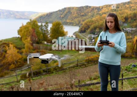 Figure floue de fille contrôle un drone sur l'automne flou arrière-plan. Consépt. De mise au point douce Banque D'Images