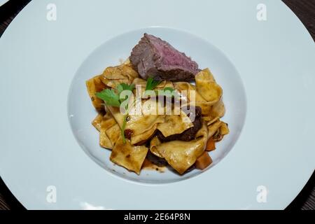 Pâtes cuites au four avec morceaux de place hachée assaisonnés de persil, servies sur une assiette Banque D'Images