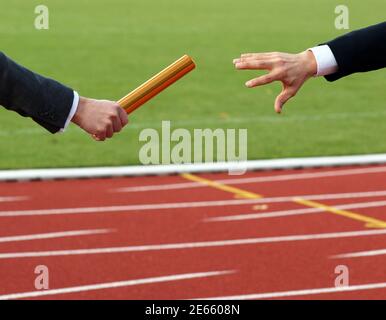 Les hommes d'affaires passent sur le bâton dans la course de relais dans le stade Banque D'Images