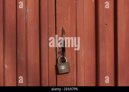 Porte métallique rouge fermée sur la clôture en acier ondulé de la serrure abri de garage pour cadenas de portail Banque D'Images