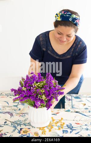 Jolie femme décorant sa table d'accueil avec une belle fleur disposition Banque D'Images