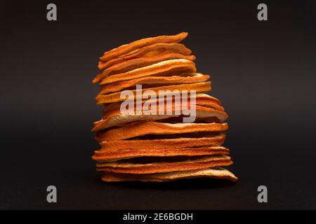 Tranchez les oranges déshydratées séchées l'une sur l'autre, dans une pile, sur fond noir Banque D'Images