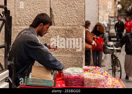 Damas, Syrie 03-28-2010: Un jeune arabe vend des bonbons délicieux sur une voiturette alimentaire dans la rue de la vieille ville de Damas. Piles de SW Banque D'Images
