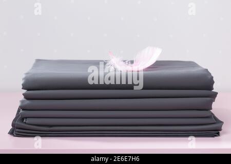 Sur la table se trouve une pile de feuilles grises vierges pliées avec une plume rose. Banque D'Images