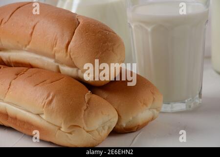 Petits pains frais et lait sur fond blanc Banque D'Images