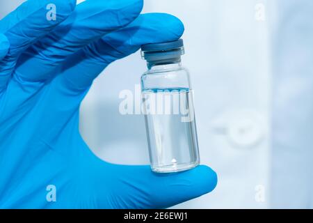 La main du médecin en gants bleus tient une bouteille médicale avec un médicament en gros plan. Concept de médecine Banque D'Images