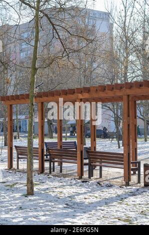 Bancs vides sous une voûte en bois sur la place de la ville. Pelouses couvertes de neige: Mykolaiv, Ukraine - 21 janvier 2021 Banque D'Images