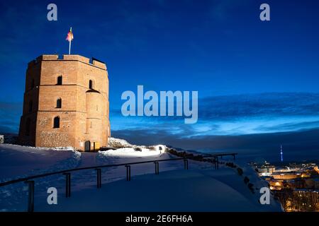 Tour ou château de Gediminas, la partie restante du château médiéval supérieur de Vilnius, Lituanie avec drapeau lituanien et tour de télévision en hiver, nuit Banque D'Images