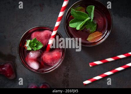 Cocktail de canneberges avec glaçons en forme de cœur sur fond sombre. Banque D'Images