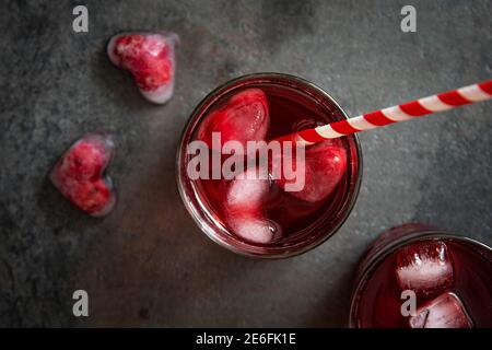 Cocktail de canneberges avec glaçons en forme de cœur sur fond sombre. Vue de dessus. Banque D'Images