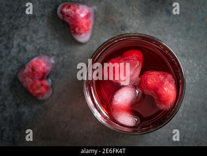 Cocktail de canneberges avec glaçons en forme de cœur sur fond sombre. Vue de dessus. Banque D'Images