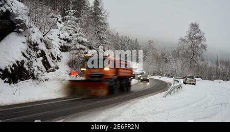Altenau, Allemagne, le 26 janvier 2021 : un véhicule de défrichage dégage une route des montagnes Harz de neige fraîchement tombée, une ligne de voitures suit le shov de neige Banque D'Images