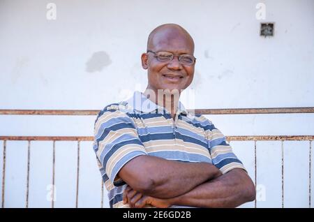 vieux africain noir portant ses lunettes avec les mains plié et souriant Banque D'Images