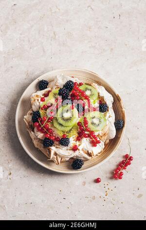 pavlova à la cannelle avec baies et kiwi sur une pierre naturelle arrière-plan texturé Banque D'Images