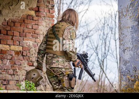 Belle fille en uniforme militaire avec un pistolet airsoft Banque D'Images