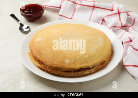 Concept de petit déjeuner avec assiette de crêpes fines et confiture sur fond blanc texturé Banque D'Images