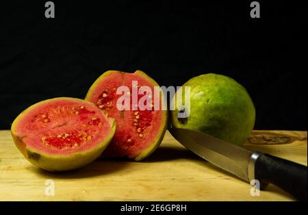 Fruits de goyave coupés en morceaux et conservés sur la table à côté d'un fruit de goyave complet Banque D'Images