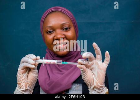 jeune femme noire belle tenant une seringue avec le vaccin d'une pandémie en elle Banque D'Images