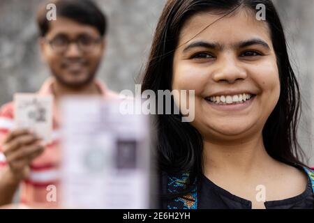 Homme et femme indiens montrant une carte de vote floue avec le sourire en attente Banque D'Images