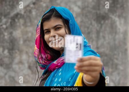 Une femme d'un village indien au visage souriant montrant un électeur flou carte en main Banque D'Images