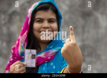 Accent sélectif sur le doigt marqué à l'encre d'une femme d'un village indien avec visage souriant et carte de vote de l'autre main Banque D'Images