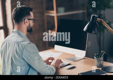 Photo portrait vue arrière de l'homme travaillant sur pc avec espace vide à l'écran à la table dans un bureau industriel moderne intérieur Banque D'Images