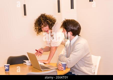Patron féminin donnant des instructions à un travailleur à une table au bureau Banque D'Images
