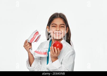 Latino Americano enfant avec un sourire Toothy, tenant un modèle de mâchoire et de pomme dans ses mains. Les fruits sont très sains pour les dents des enfants Banque D'Images