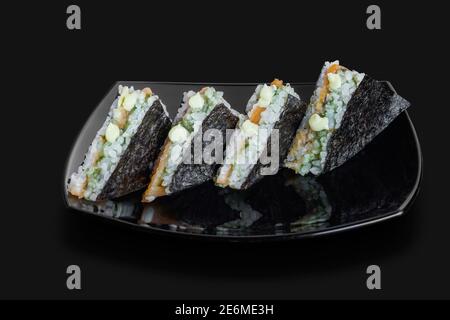 Sandwich de sushis japonais fraîchement confectionnés servi dans un noir plaque Banque D'Images