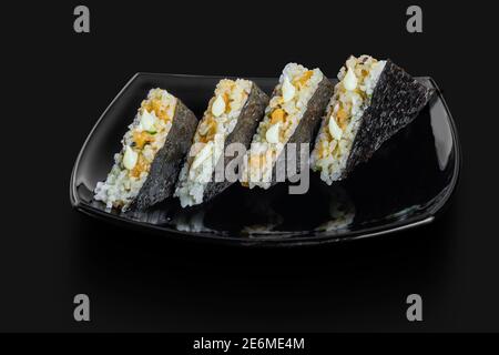 Sandwich de sushis japonais fraîchement confectionnés servi dans un noir plaque Banque D'Images