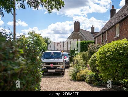 Mariage beau beau poli propre classique camionnette de camping avec rubans roses garé sur l'allée à l'extérieur d'un chalet de campagne sous le soleil vous attendant pour mariée Banque D'Images