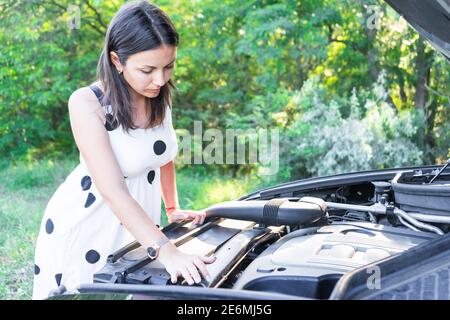 une jeune femme répare une voiture cassée. réparer une voiture. belle dame et voiture Banque D'Images