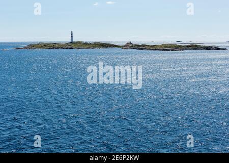 Petite île avec un phare près de la côte de Norvège Banque D'Images