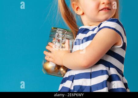 Petite fille mignonne tenant un pot en verre avec des œufs dorés de couleur Pour Pâques Banque D'Images