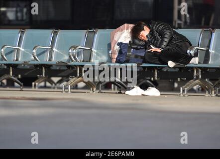 Fuyang, Chine. 29 janvier 2021. Un passager dormant en attendant avant de prendre son train à la gare de Fuyang.alors que la course de voyage du Spring Festival a commencé, les opérateurs de transport ont resserré les mesures pour empêcher la résurgence des cas de COVID-19 (coronavirus) en rendant obligatoire le masque facial pour tous les passagers de la gare. Selon le ministère, environ 1.15 milliards de voyages de passagers devaient être effectués pendant la période de 40 jours, soit une baisse de 20 % d'une année sur l'autre et plus de 60 % de moins qu'en 2019. Crédit : SOPA Images Limited/Alamy Live News Banque D'Images