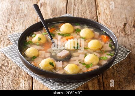 Soupe fraîche maison avec jambon, légumes et boulettes de semoule de maïs dans une assiette sur la table. Horizontale Banque D'Images