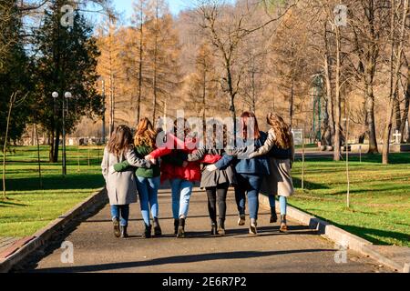 Jeune groupe de filles marchant dans le parc d'automne, vêtements d'automne et marche d'automne. Diplôme du secondaire 2021. Banque D'Images